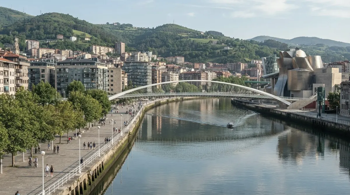 The river in Bilbao with a white arched footbridge, a riverside promenade and a modern museum with curved metal walls